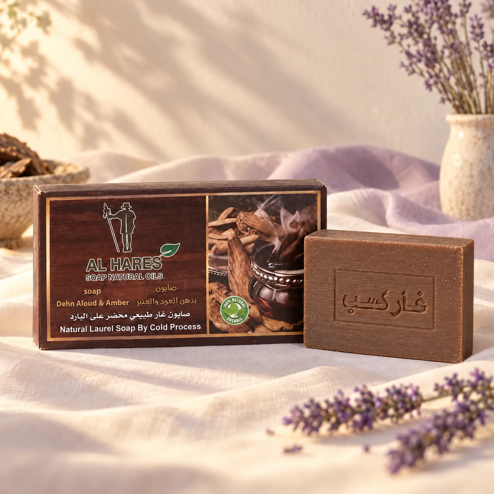 Savon Al Hares oud et ambre devant sa boîte brune avec deux éclats d’ambre