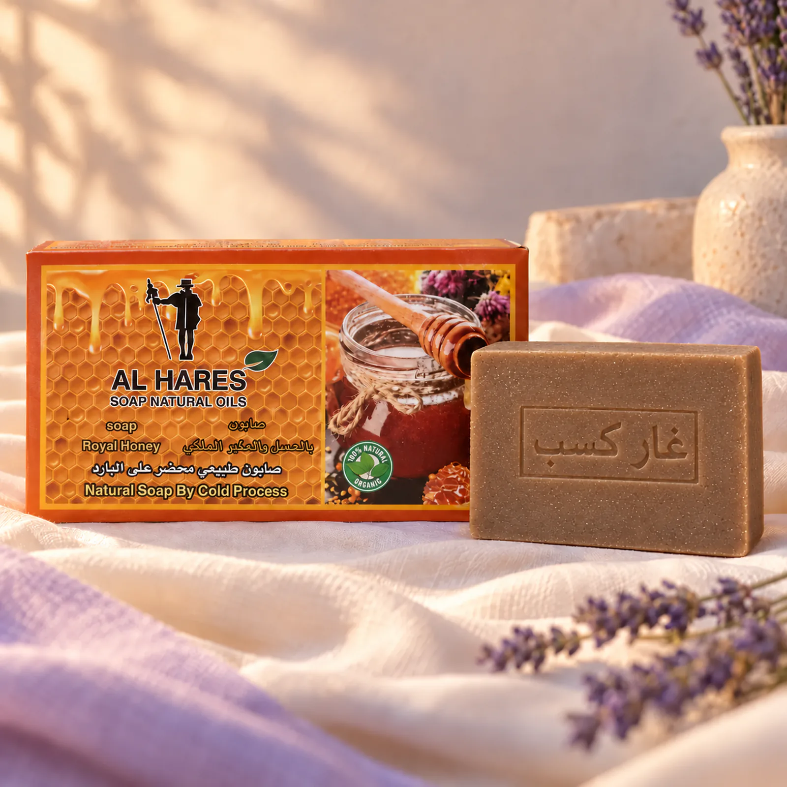 Savon Al Hares au miel posé devant sa boîte orange avec un morceau de rayon de miel